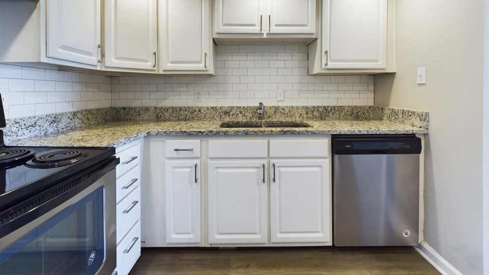 a kitchen with white cabinets and stainless steel appliances at The Edgewater