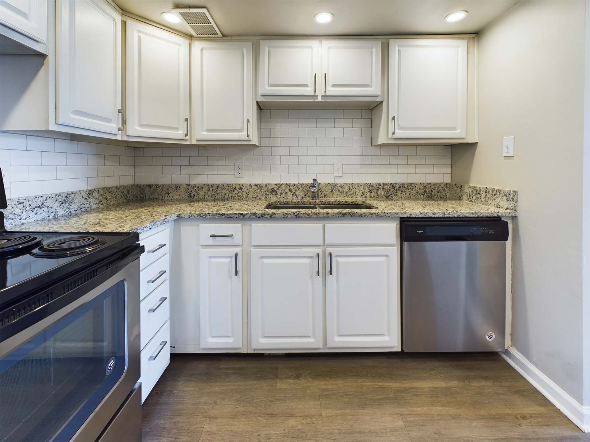 a kitchen with white cabinets and stainless steel appliances at The Edgewater