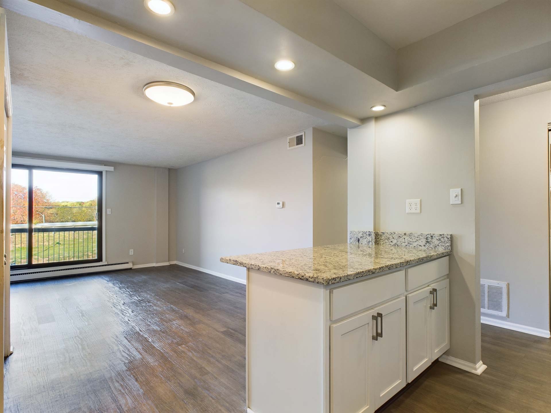 an empty kitchen with white cabinets and hardwood floors at The Edgewater