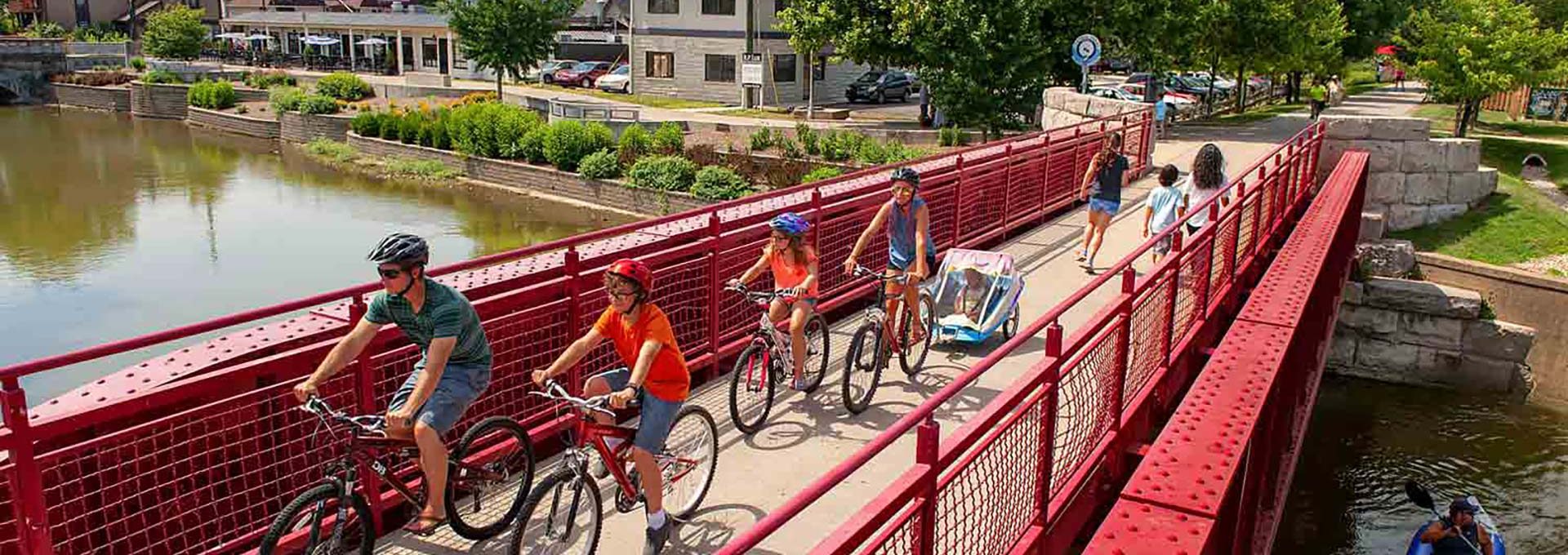 people riding bikes on a red bridge over a river at The Edgewater